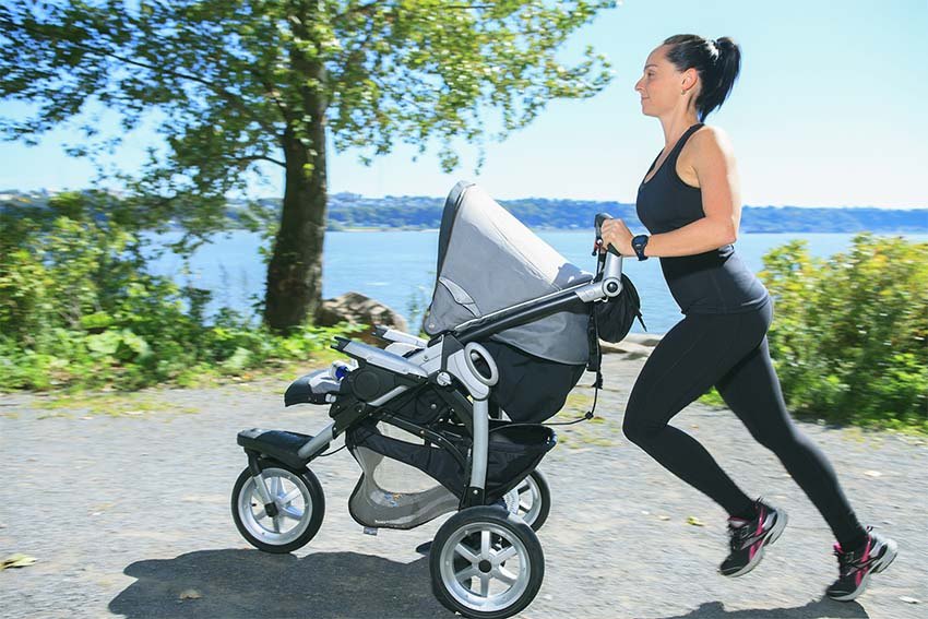 A Young mother jogging with a baby buggy